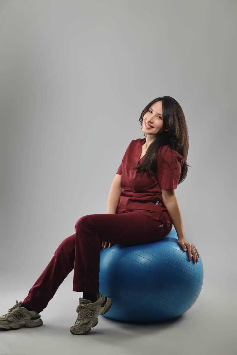 Une femme est assise sur un ballon d'exercice bleu.