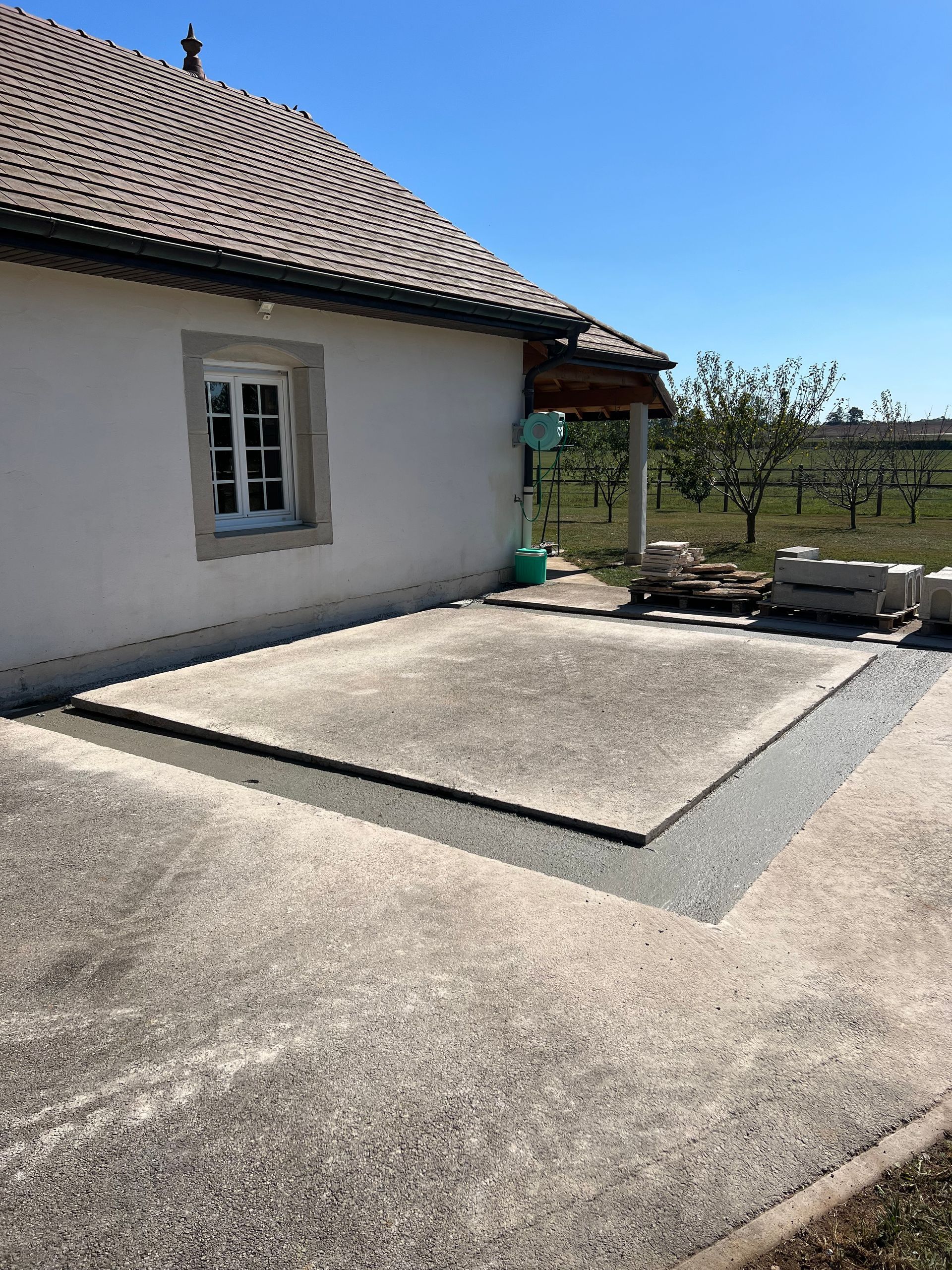Maison en béton avec un toit brun et un petit porche.