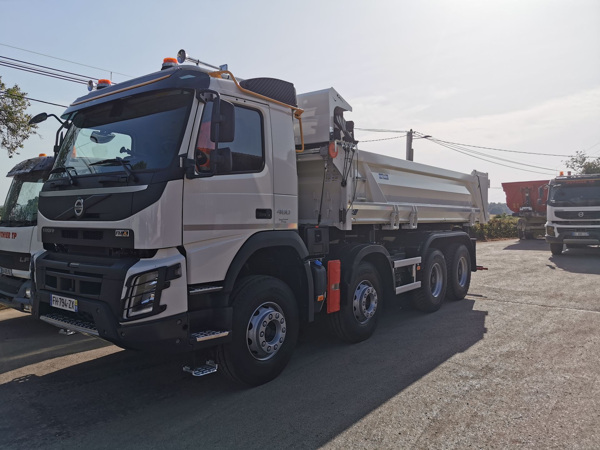 Camion-benne Volvo blanc stationné.