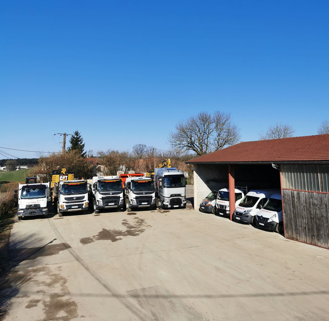 Camions garés devant un hangar par une journée ensoleillée.