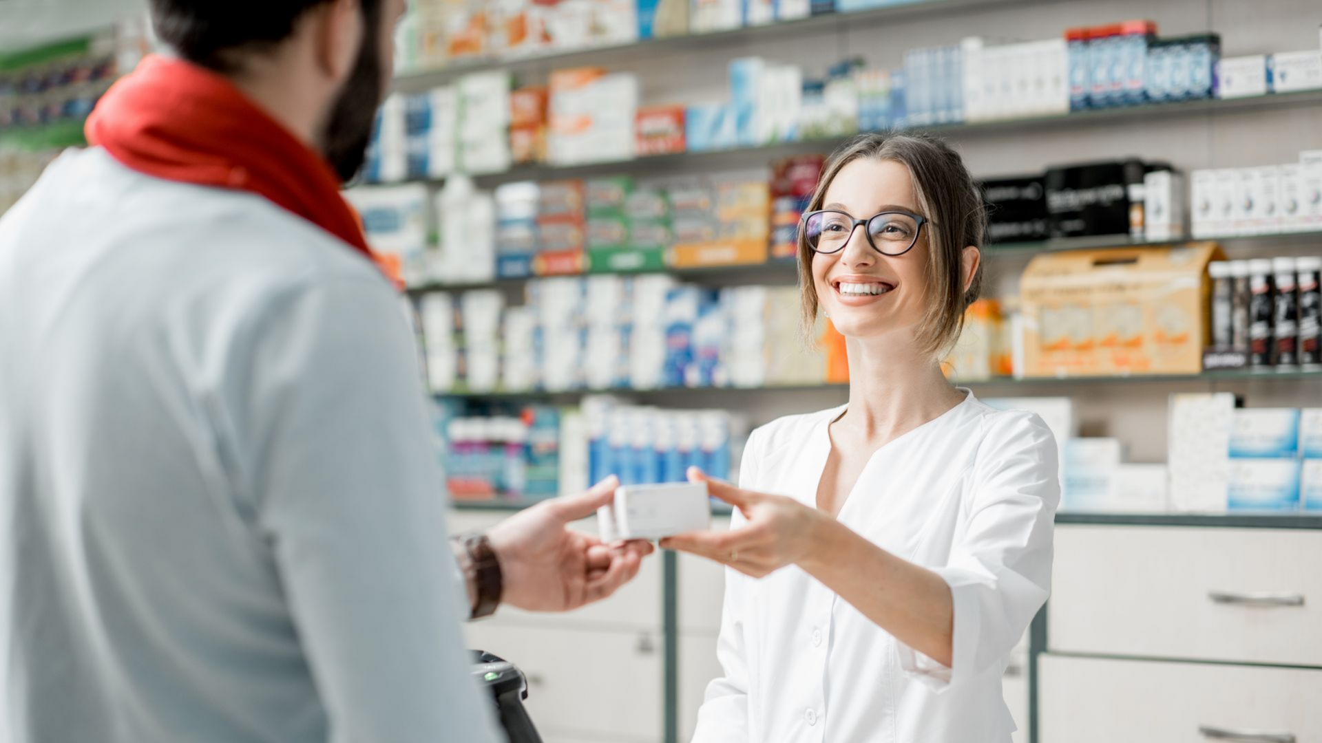 Une pharmacienne remettant un médicament à un client.