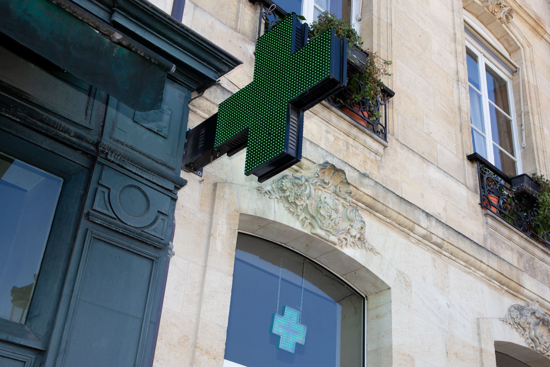 Une enseigne de pharmacie fixée sur une façade de bâtiment.