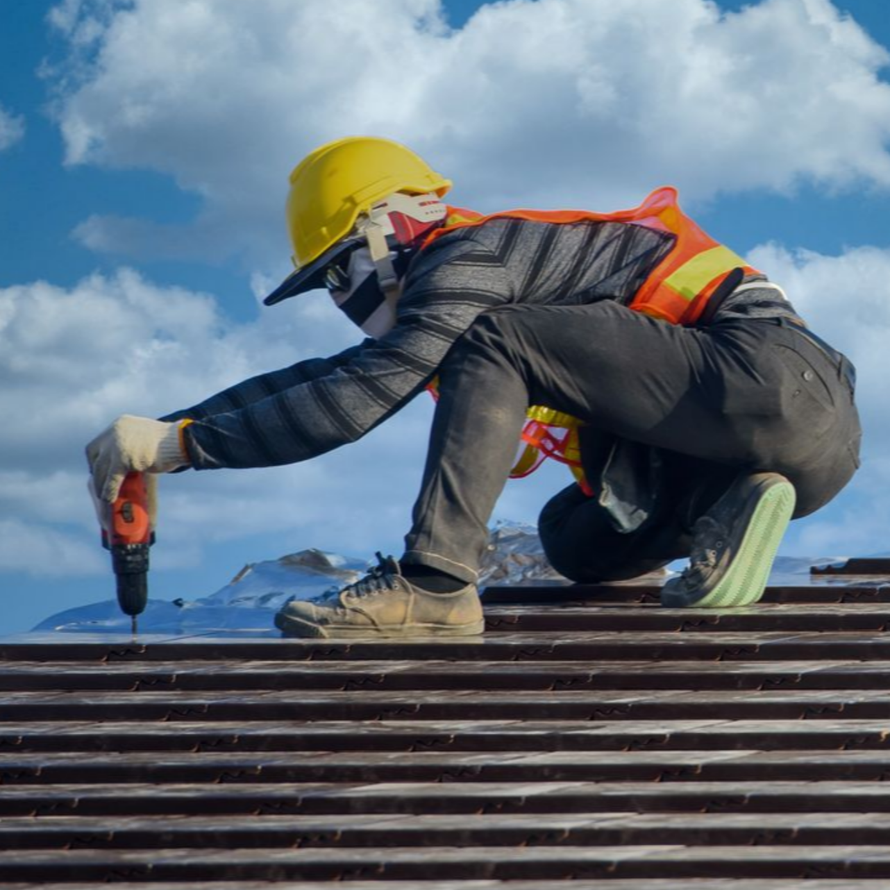 Un couvreur sur un toit et des nuages