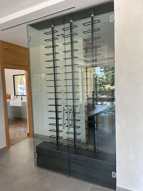 Vitrina de cristal para vinos con estantes de metal negro en un interior de hogar moderno