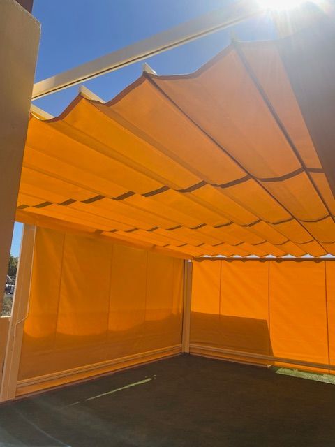 Carpa naranja con techo inclinado, vista desde el interior bajo la luz del sol.