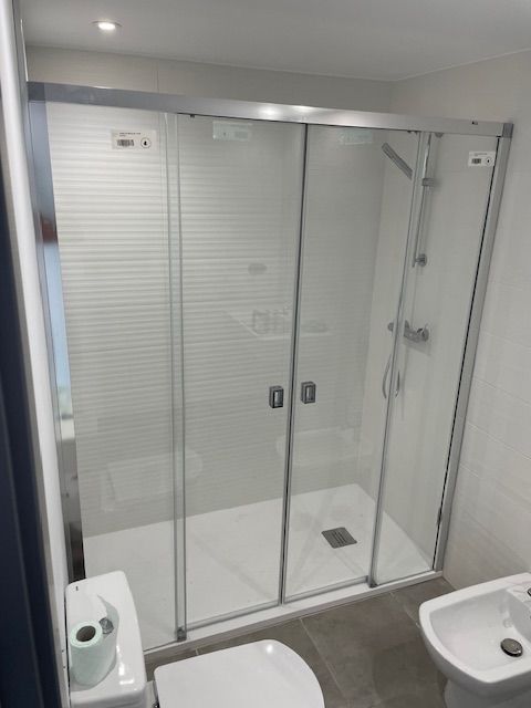 Baño pequeño con cabina de ducha de cristal, inodoro y lavabo.