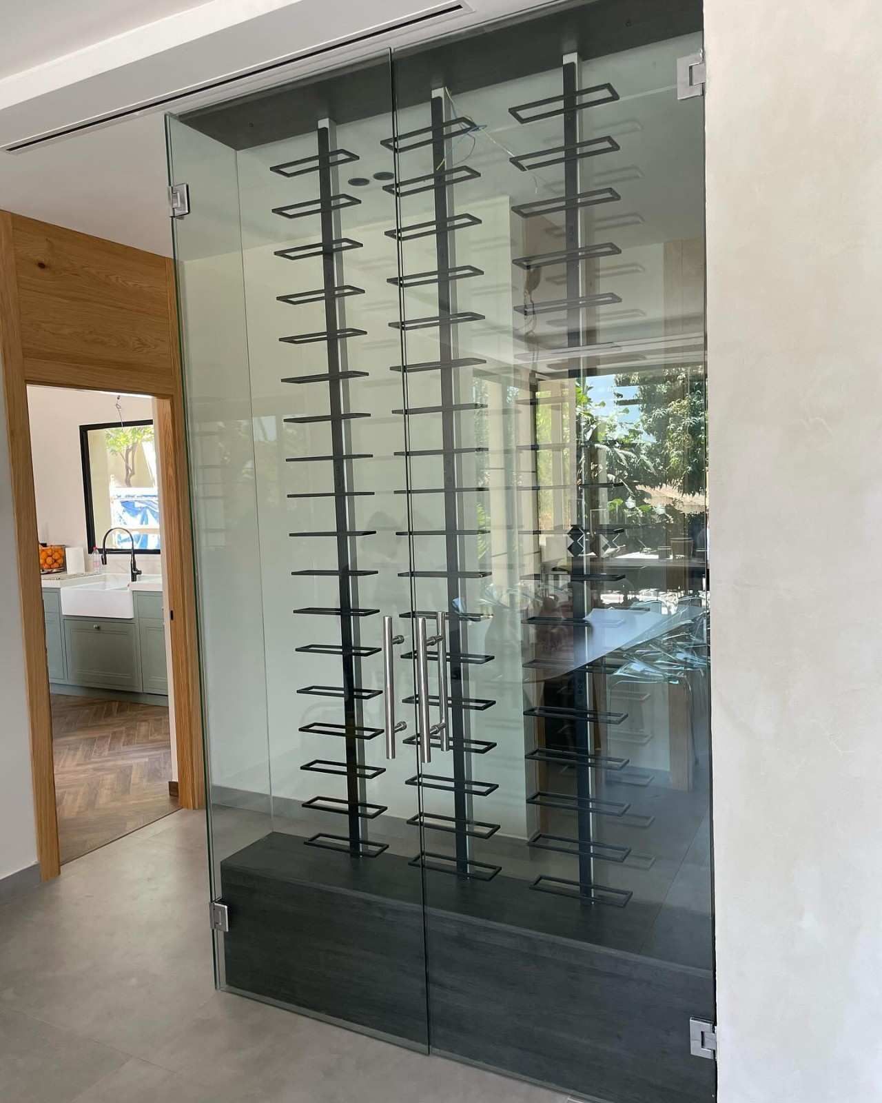 Vitrina de cristal con varias filas de gafas en un pasillo interior moderno.