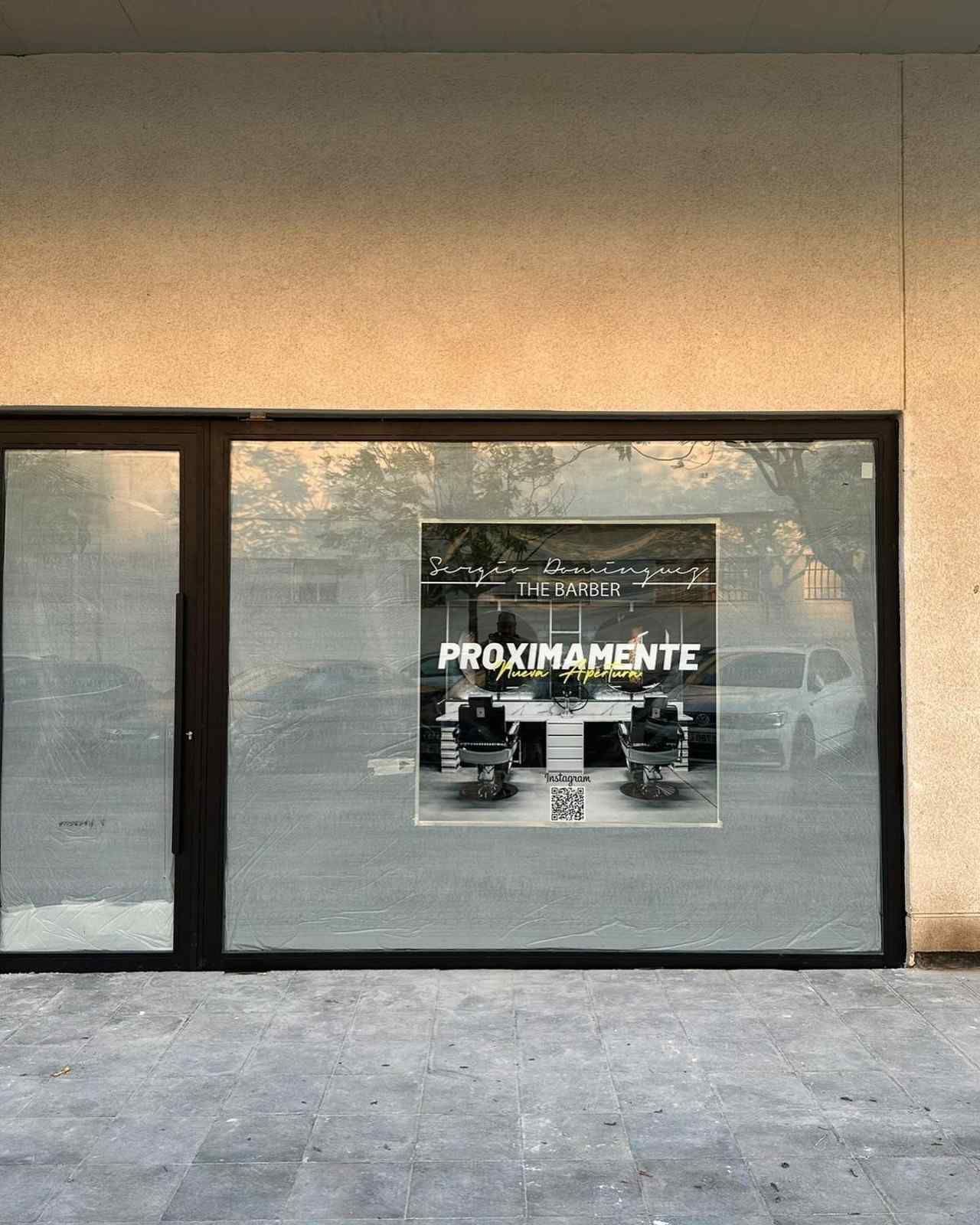 Escaparate con un letrero que dice “PRÓXIMAMENTE” y reflejos en el cristal.