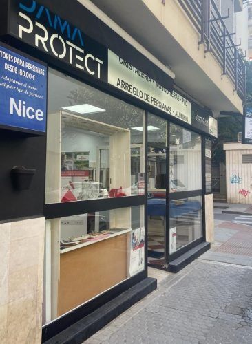 Fachada de tienda con ventanas de cristal y un letrero en blanco y negro que dice