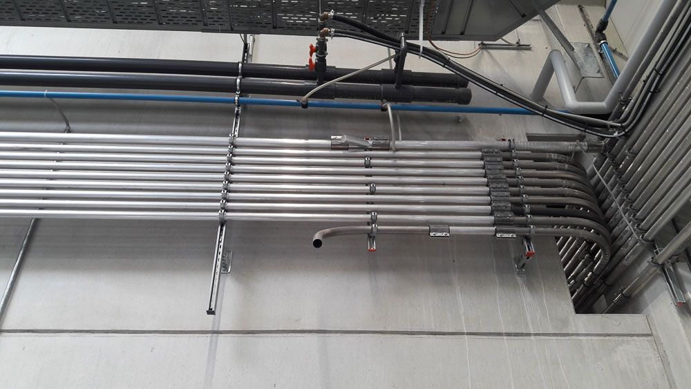 Von der Decke eines Gebäudes hängen mehrere Rohre - KID GmbH Anlagenbau in Bad Hersfeld