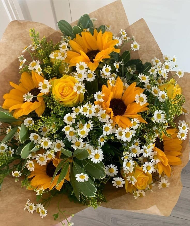 Bouquet de marguerites jaunes et blanches enveloppé dans du papier kraft.