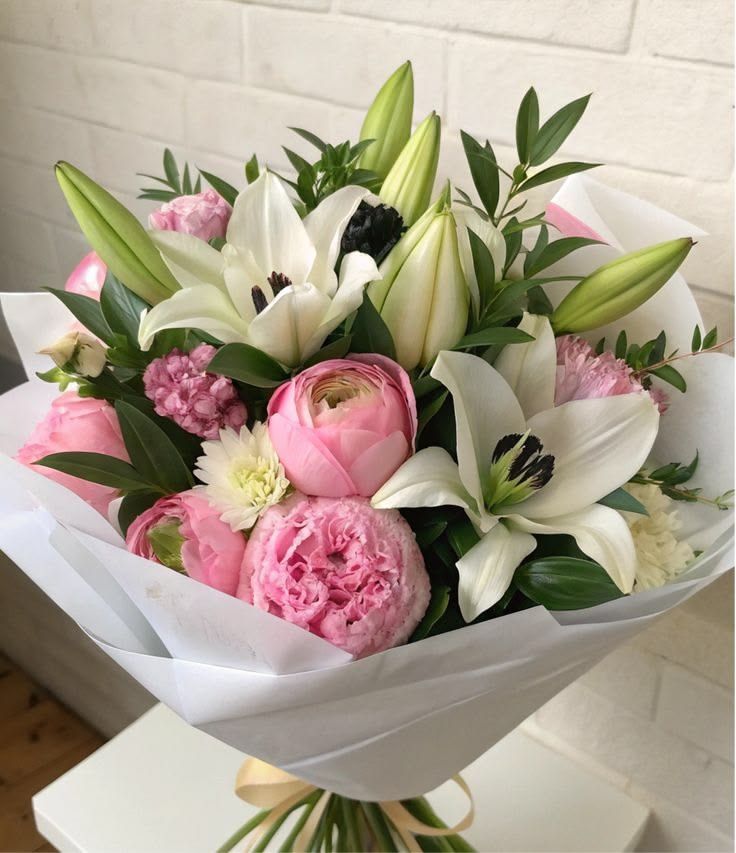 Bouquet de tulipes roses et blanches enveloppé dans du papier blanc.