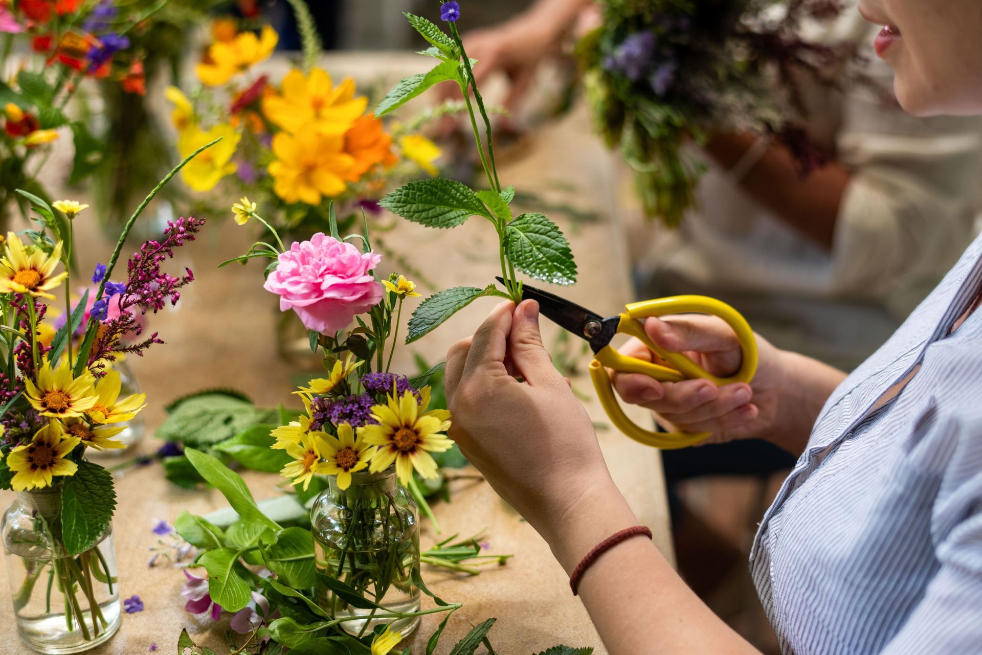 Une personne arrangeant un bouquet de fleurs colorées sur un marché en plein air.