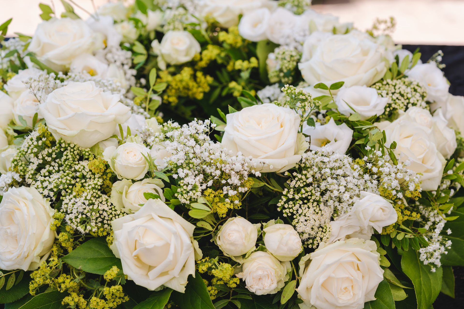 Un bouquet floral luxuriant composé de roses blanches et de gypsophile, agrémenté de feuilles vertes.
