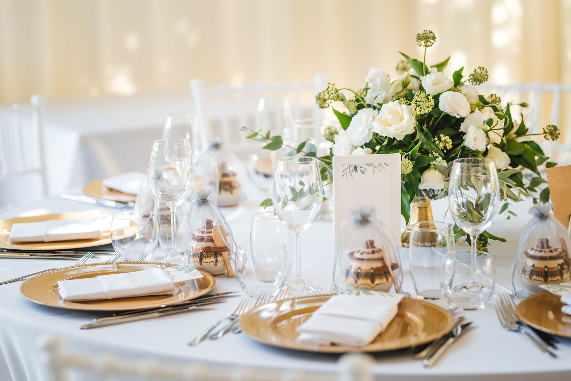 Élégante table de réception de mariage avec des couverts blancs et or et un centre de table floral.