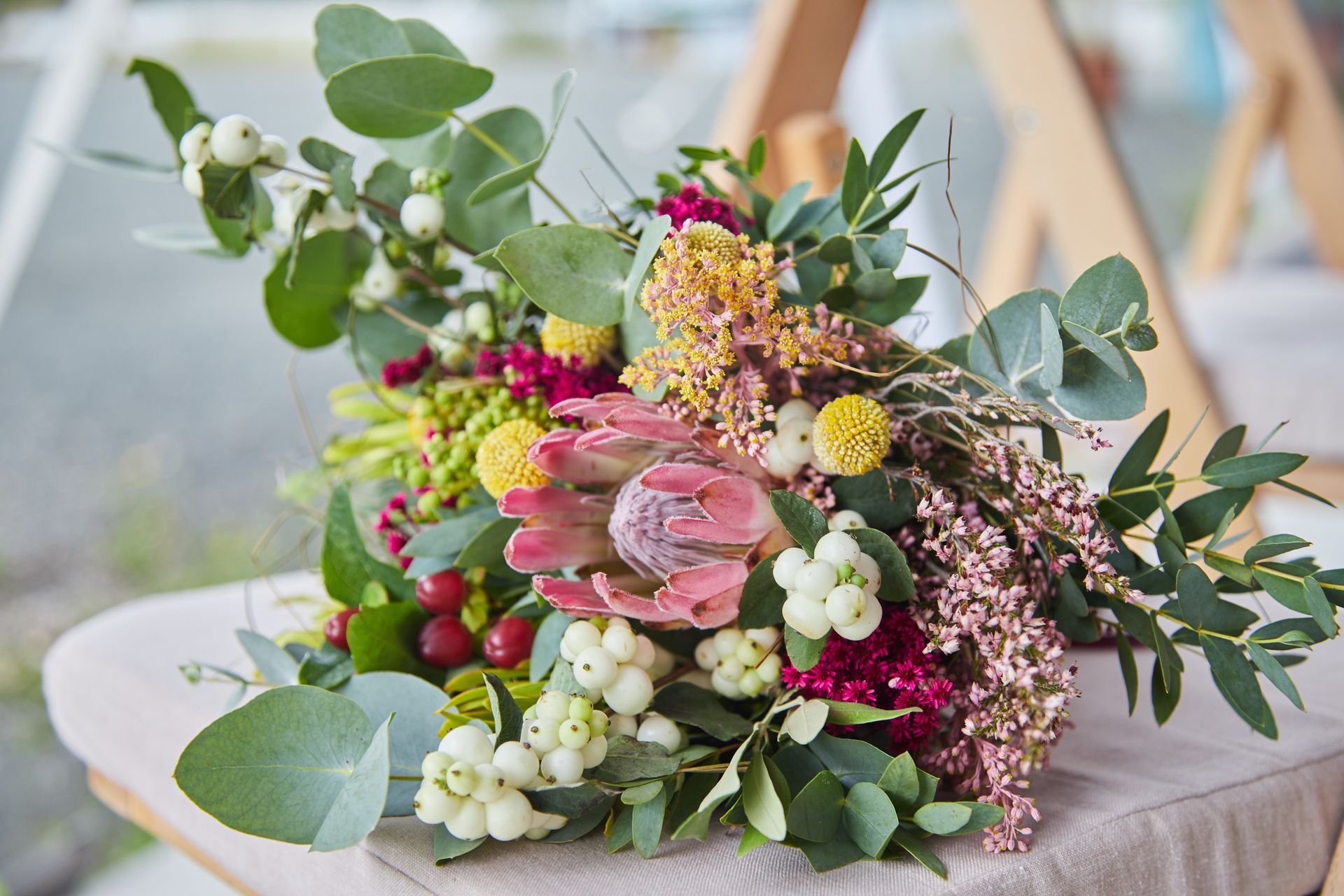 Bouquet de fleurs roses, blanches et jaunes avec de l'eucalyptus sur une table de couleur claire.