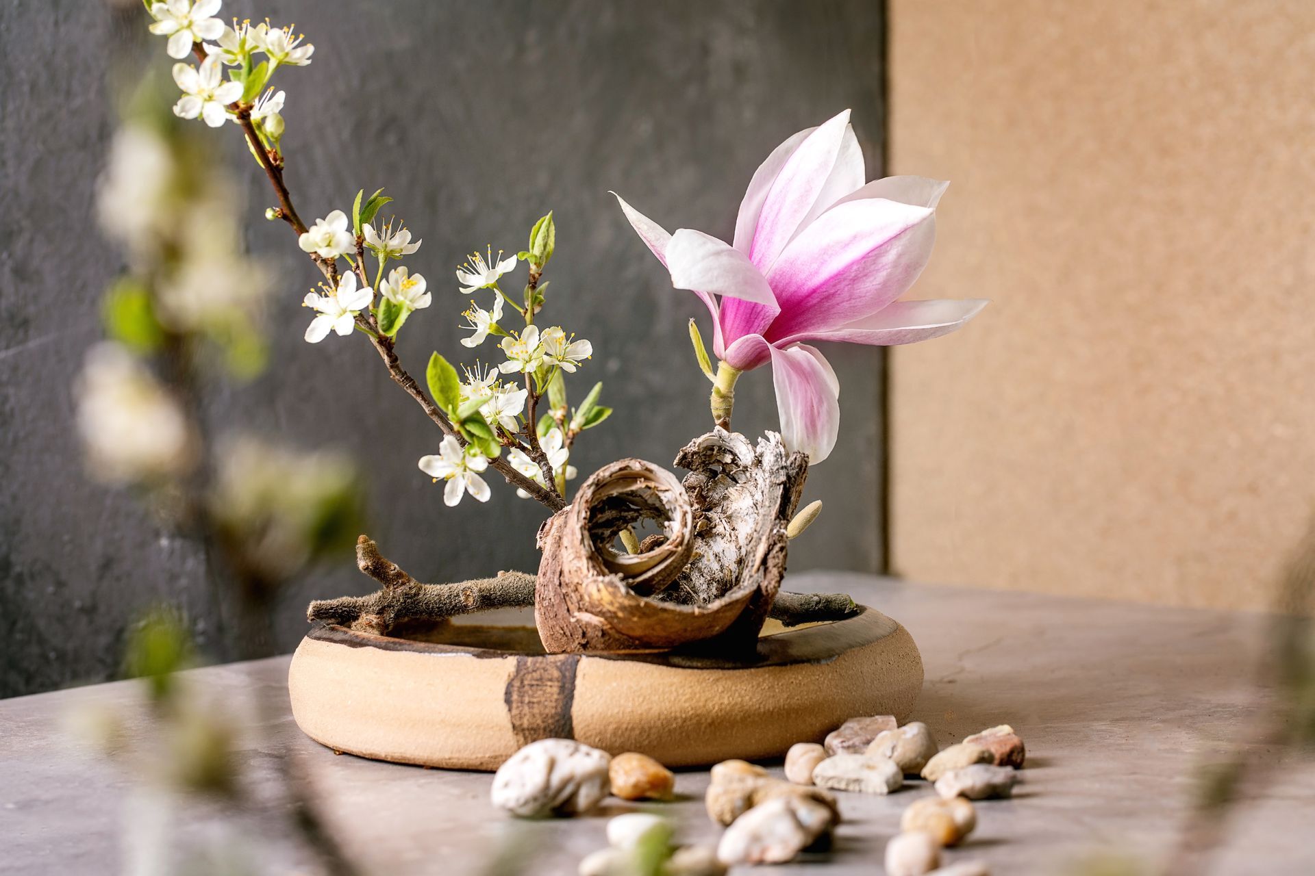 Plateau de table zen avec une petite sculpture d'escargot, une fleur rose, des fleurs blanches.