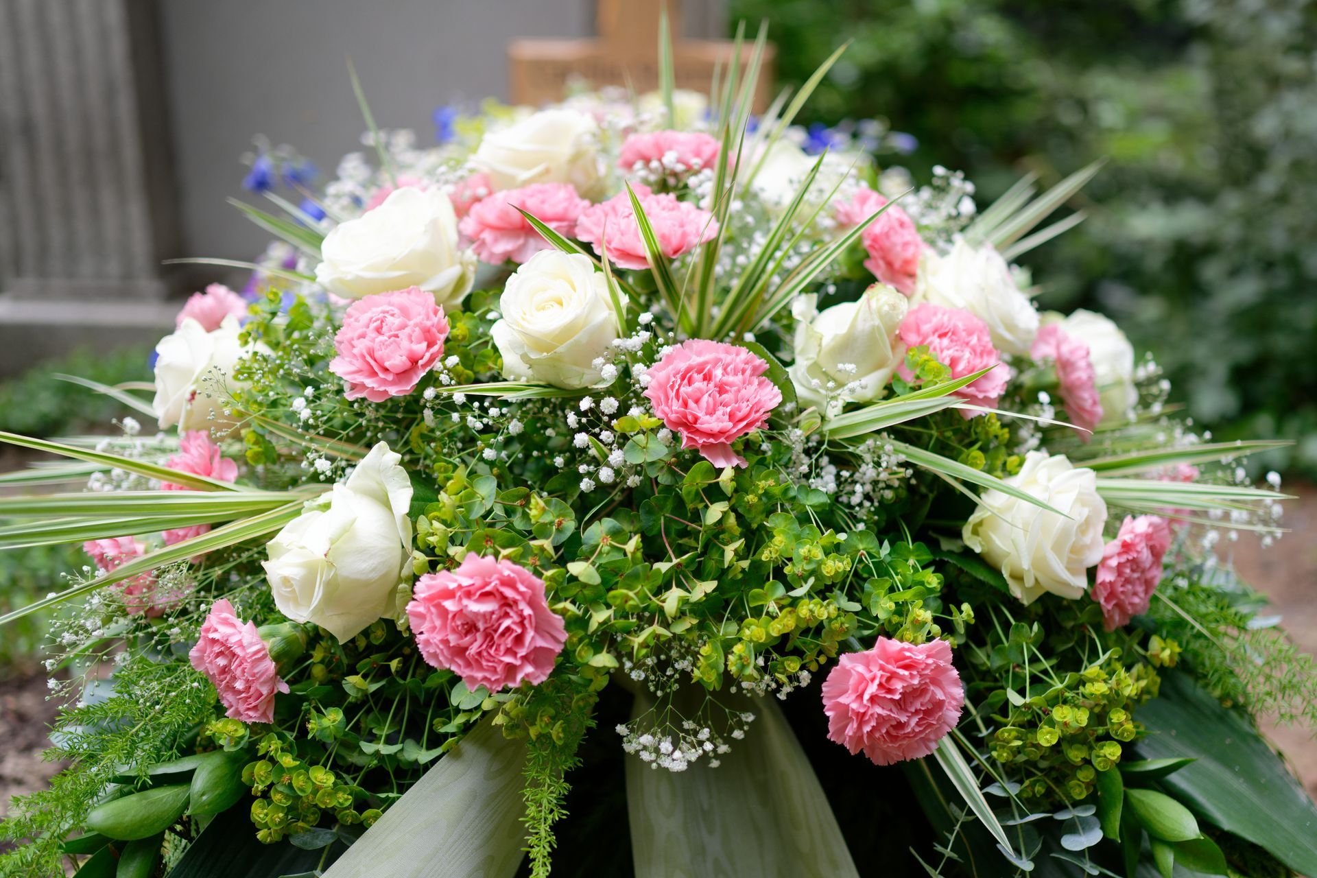 Bouquet coloré de roses blanches et roses avec de la verdure, disposé en une composition florale arrondie.