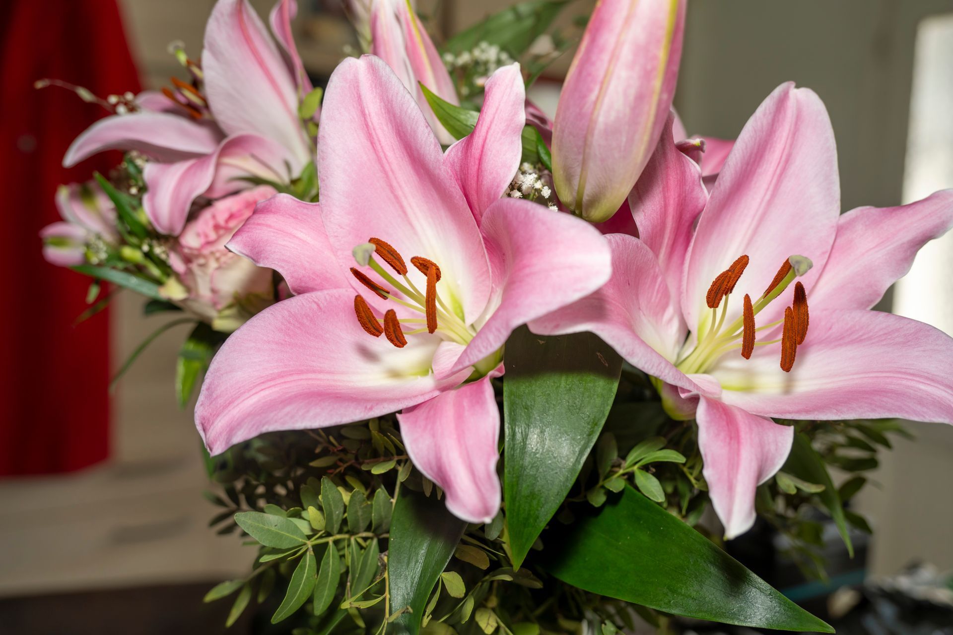 Un bouquet de lys roses en fleurs, aux feuilles vertes et aux boutons rouges.