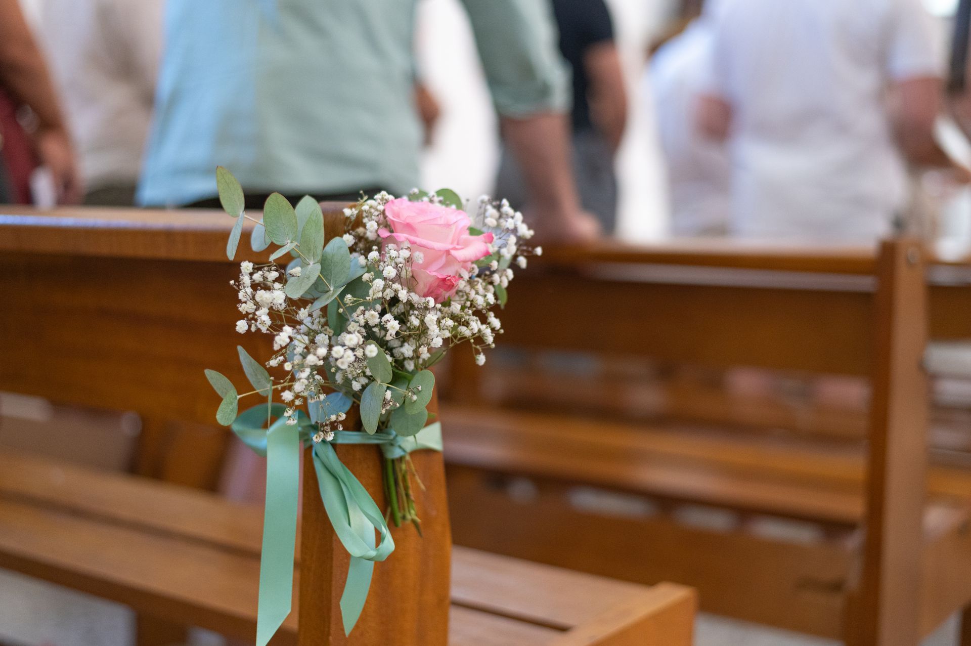 Bouquet de fleurs roses et blanches noué à un ruban en bois pour banc d'église.