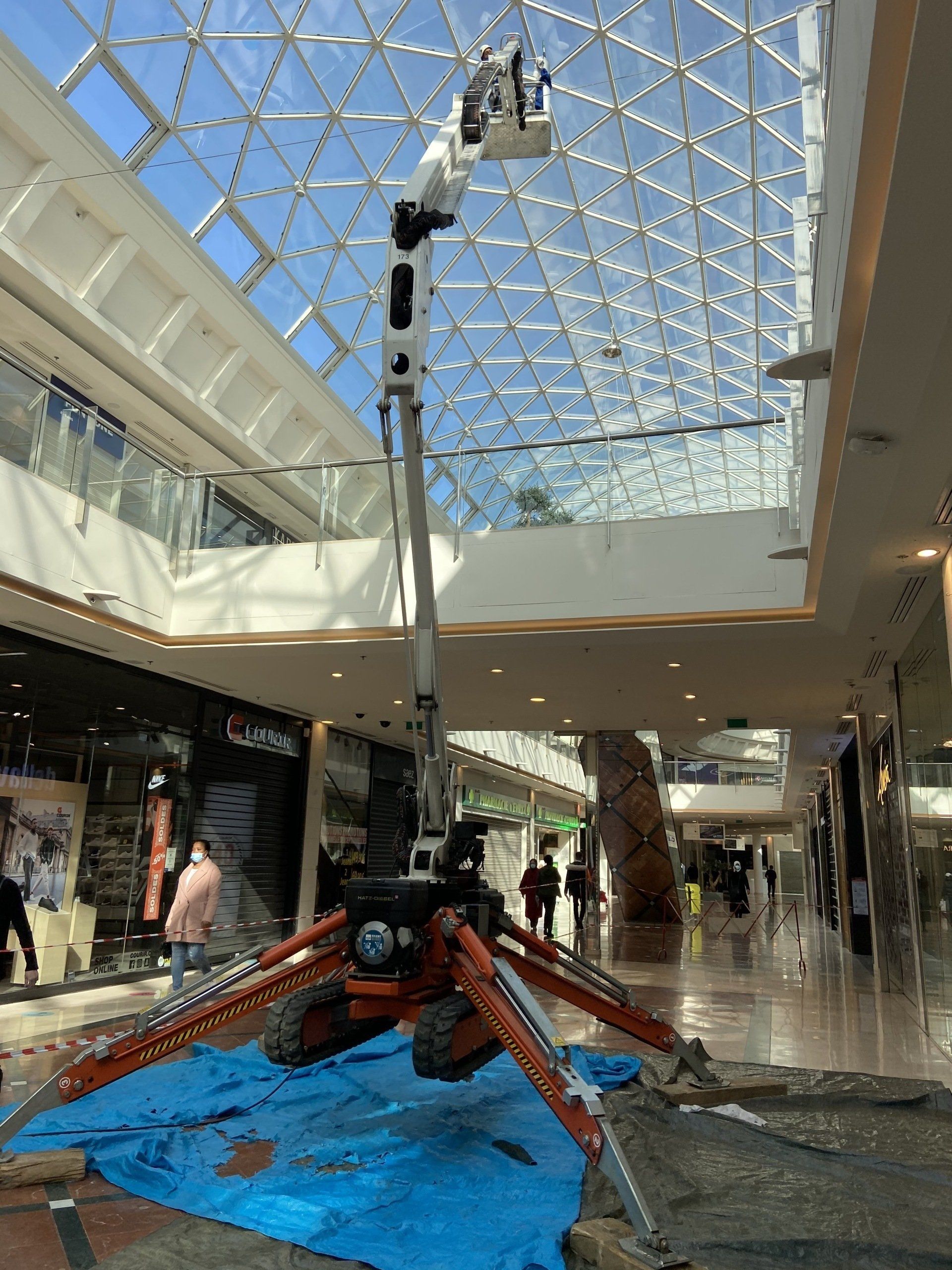 Ascenseur araignée à l'intérieur d'un centre commercial, s'élevant vers un plafond de verre.