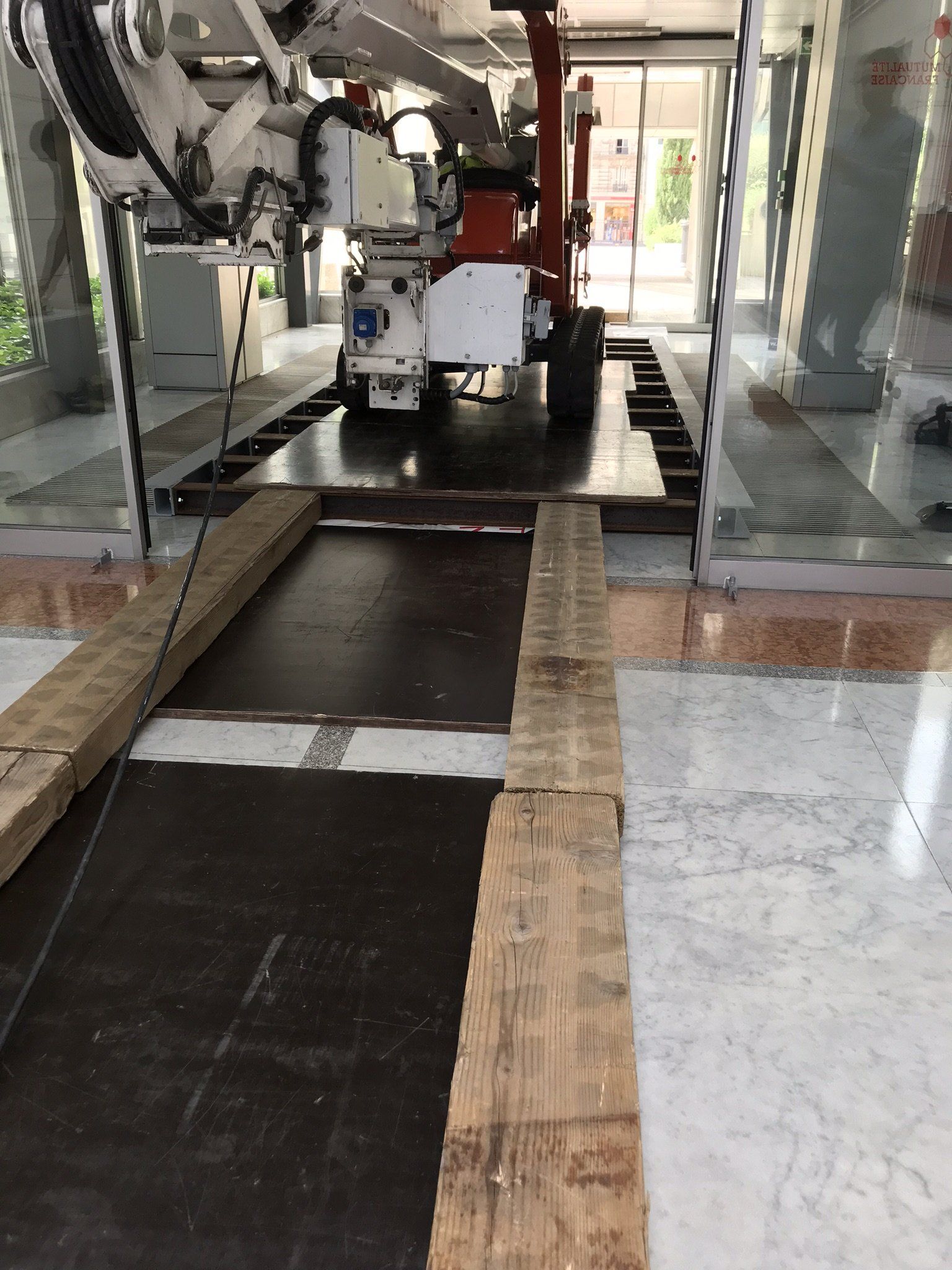 Bras robotisé dans un environnement industriel, avec des planches de bois faisant office de rampe de fortune.