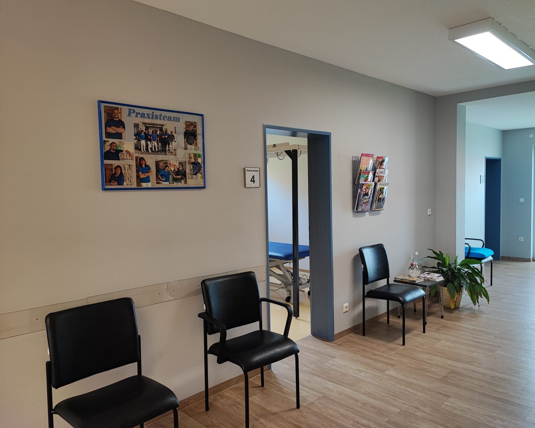 Wartezimmer mit schwarzen Stühlen, einem blauen Foto und einer offenen Tür.