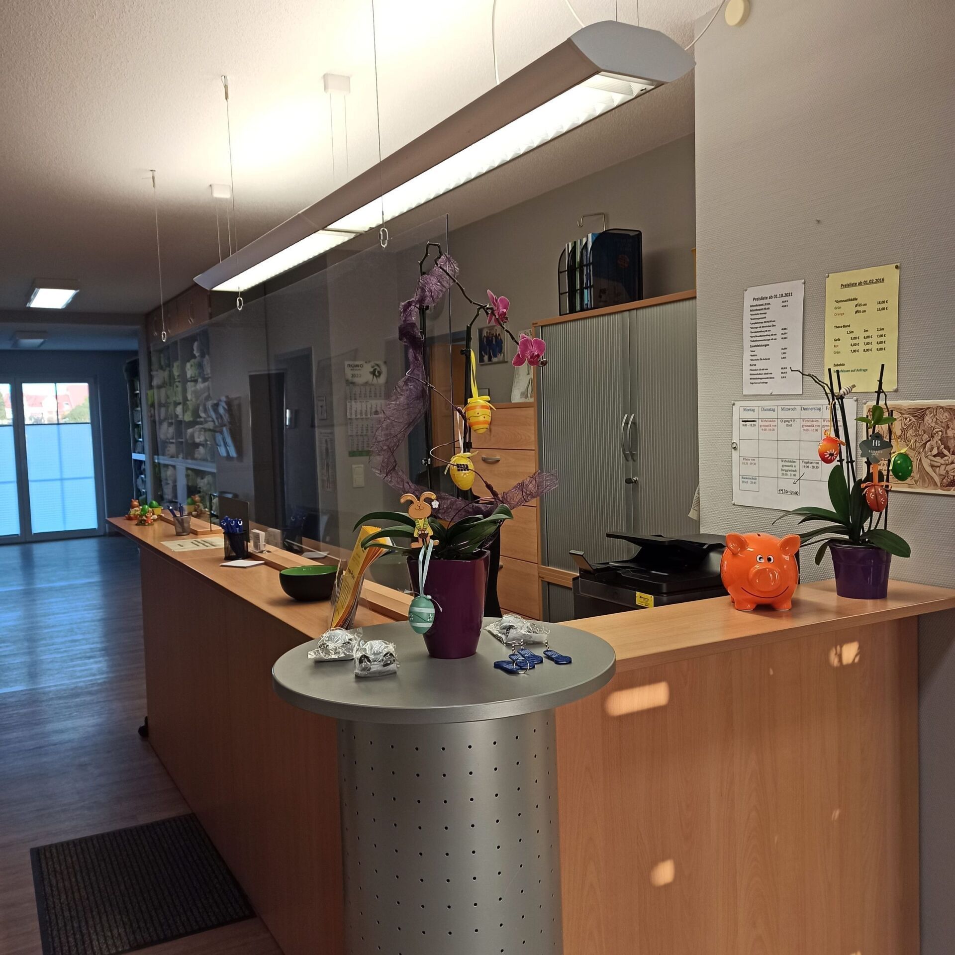 Empfangstresen mit Orchideen, Dekorationen und einem kleinen runden Tisch.