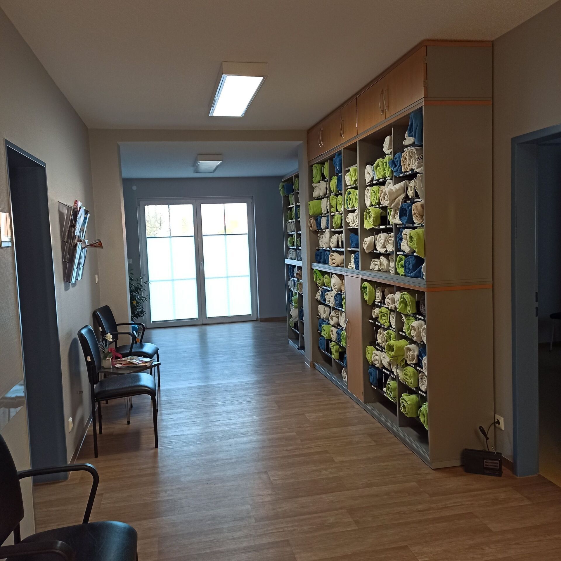 Flur mit Schuhschränken und Sitzgelegenheiten, der zu einer Tür mit Tageslicht führt.