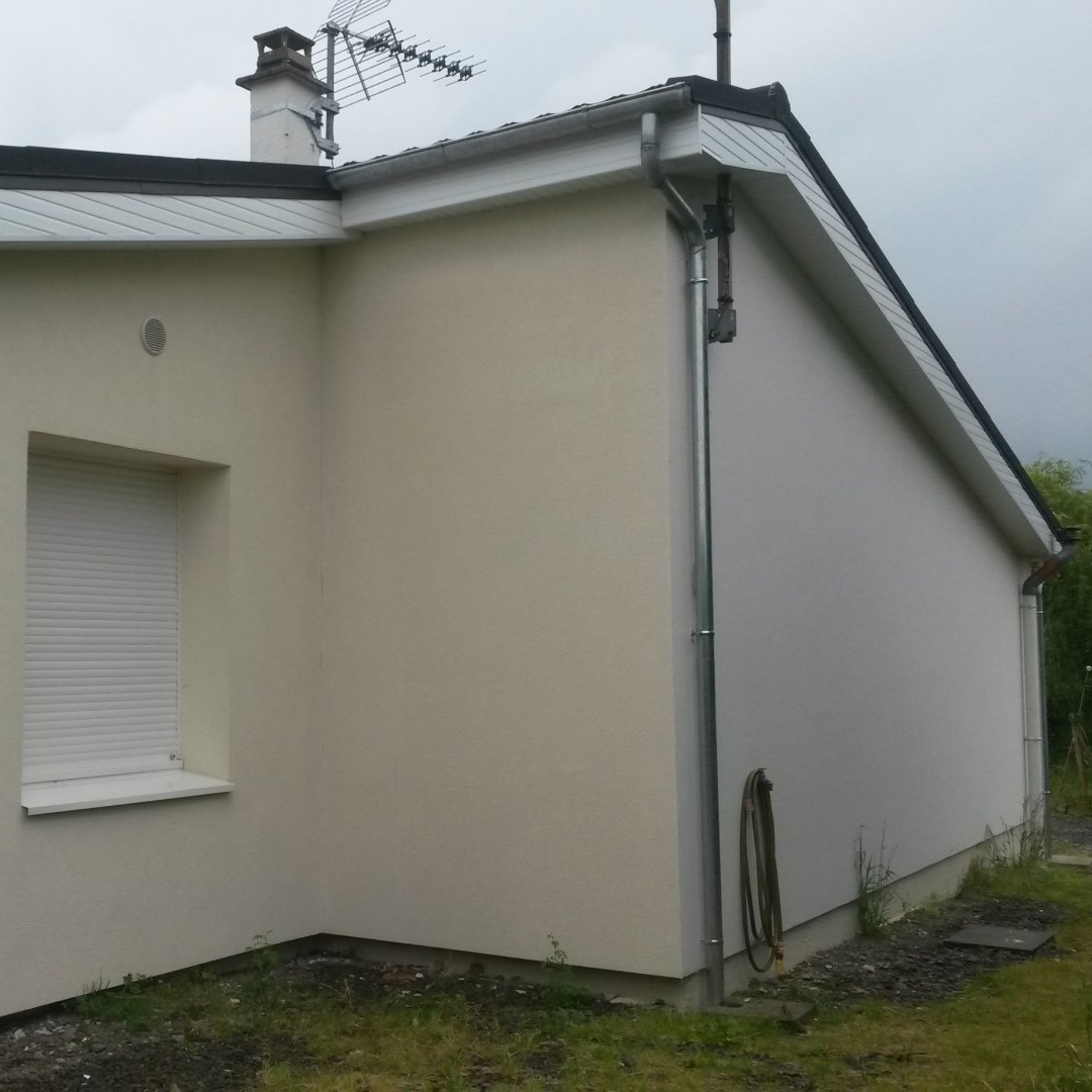 Maison de couleur beige avec fenêtre, descente de gouttière et antenne.