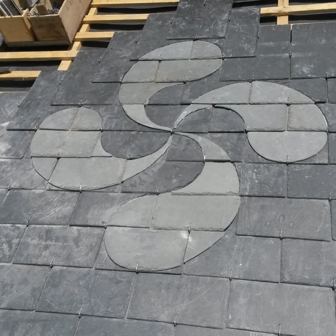 Toiture en ardoise sombre, ornée d'un lauburu en ardoise claire, symbole basque.