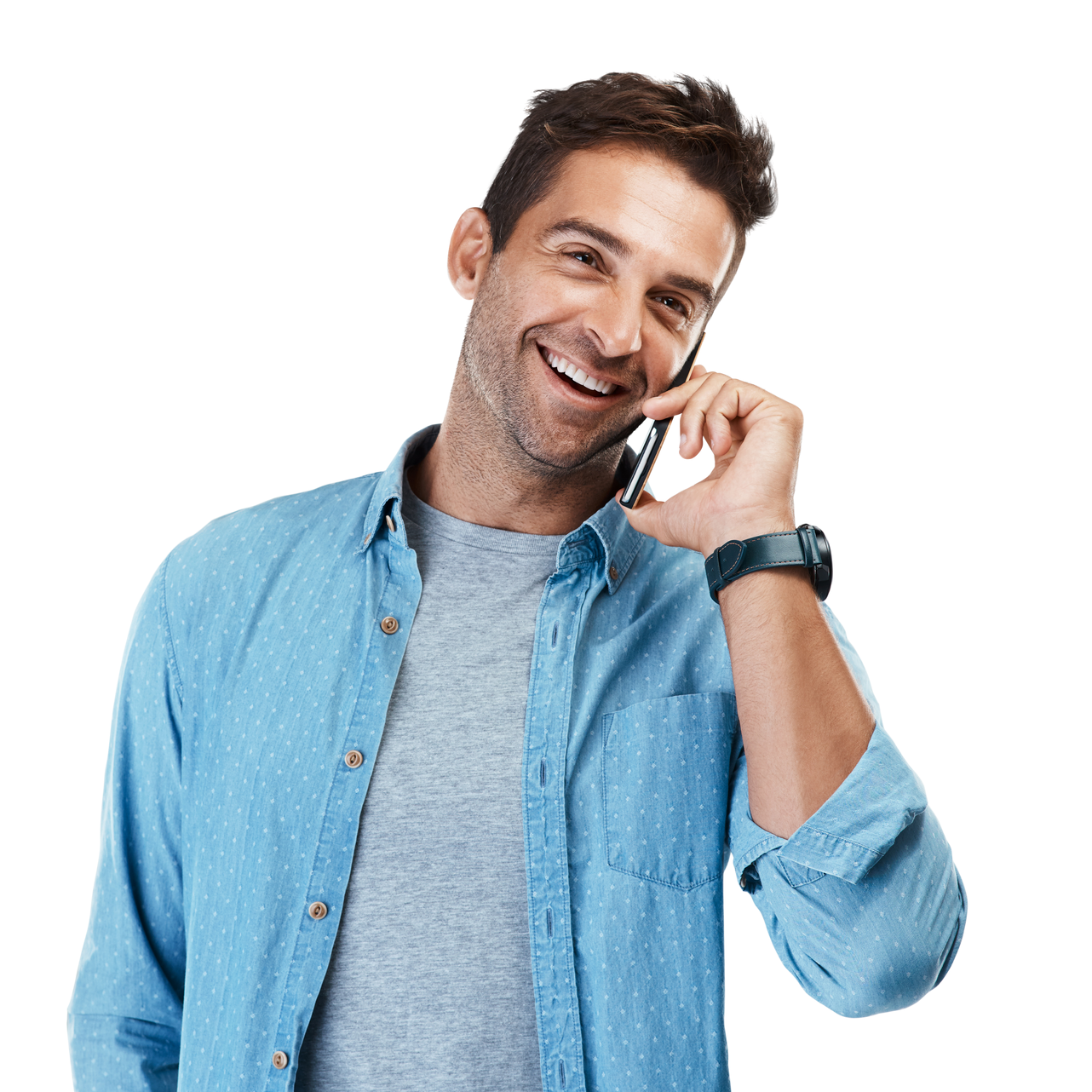 Un homme souriant parle au téléphone portable, vêtu d'une chemise bleue et d'un t-shirt gris.