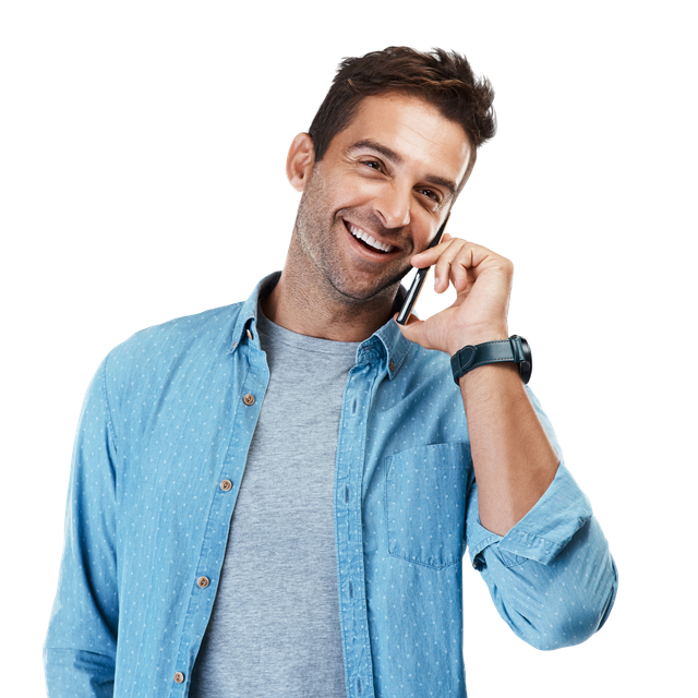 Un homme souriant parle au téléphone portable, vêtu d'une chemise bleue et d'un t-shirt gris.