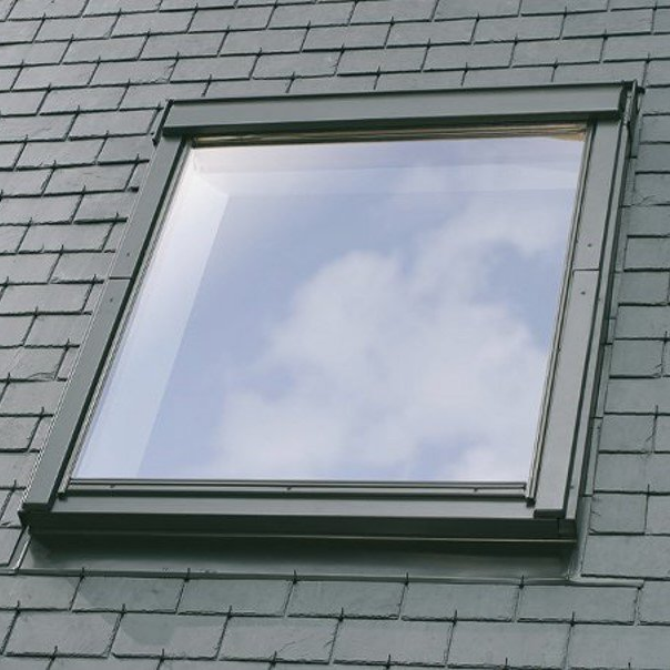 Fenêtre de toit sur un toit d'ardoise, avec le reflet des nuages.
