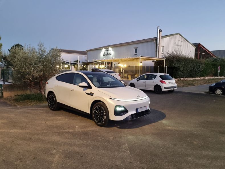 Voiture blanche garée devant un restaurant éclairé au crépuscule
