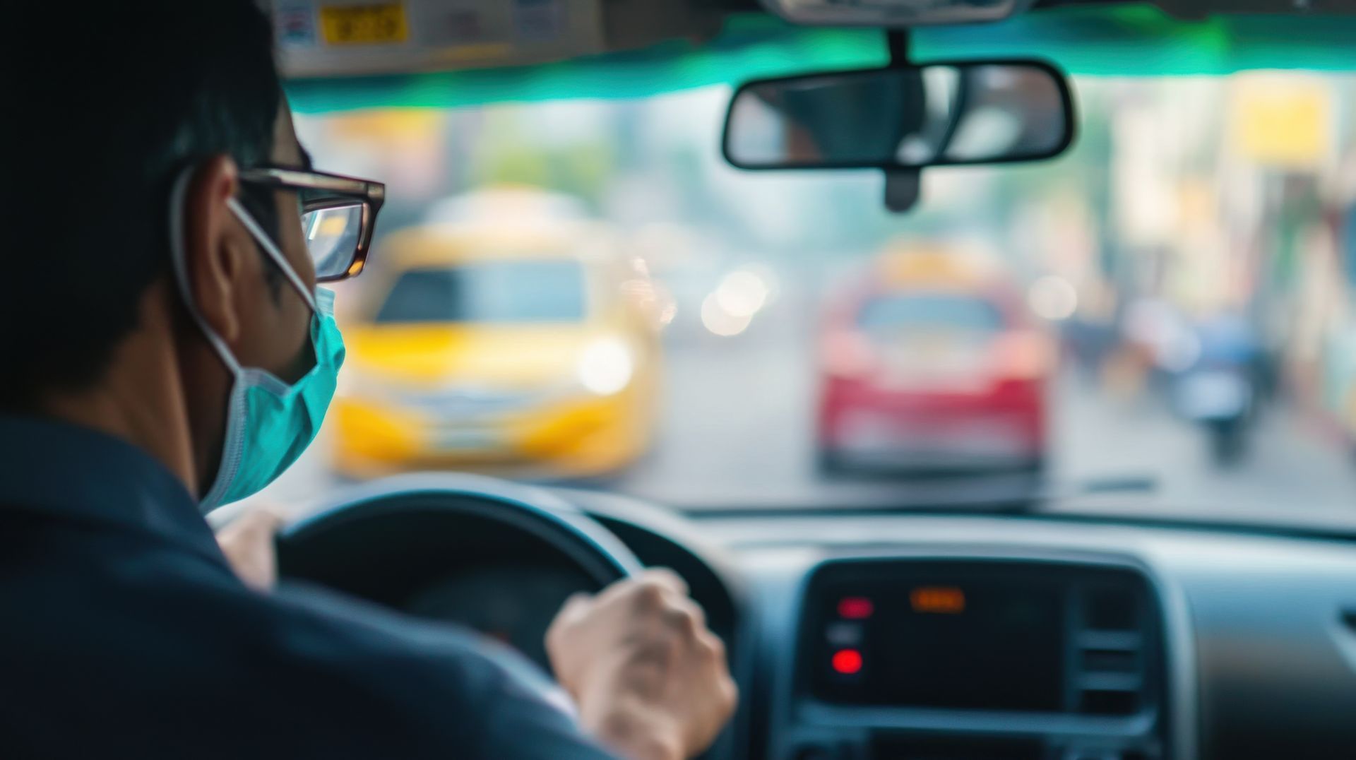Un chauffeur de taxi portant des lunettes et un masque circule dans une rue animée de la ville.