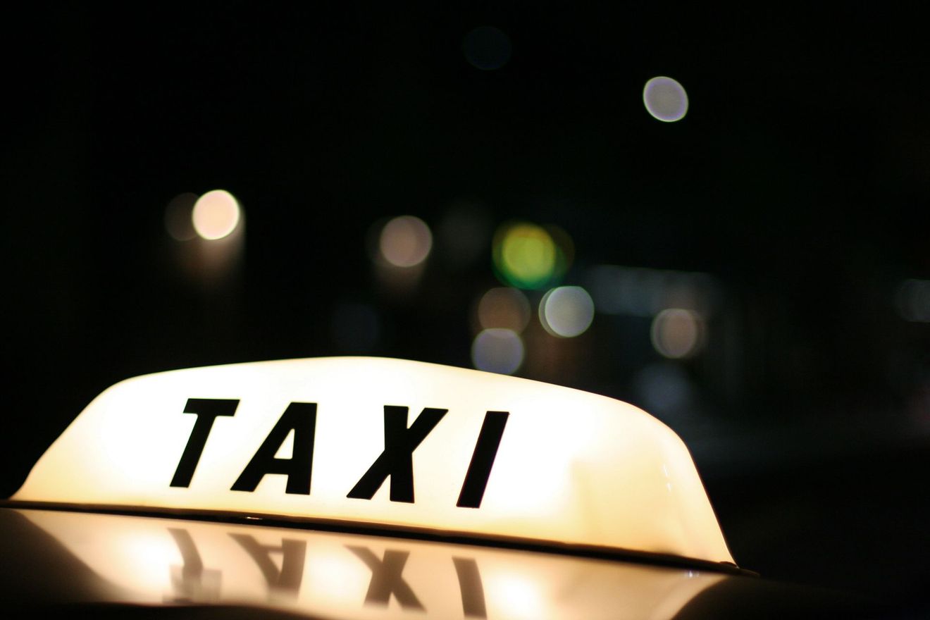 Panneau lumineux de taxi la nuit, avec les lumières de la ville floues en arrière-plan.