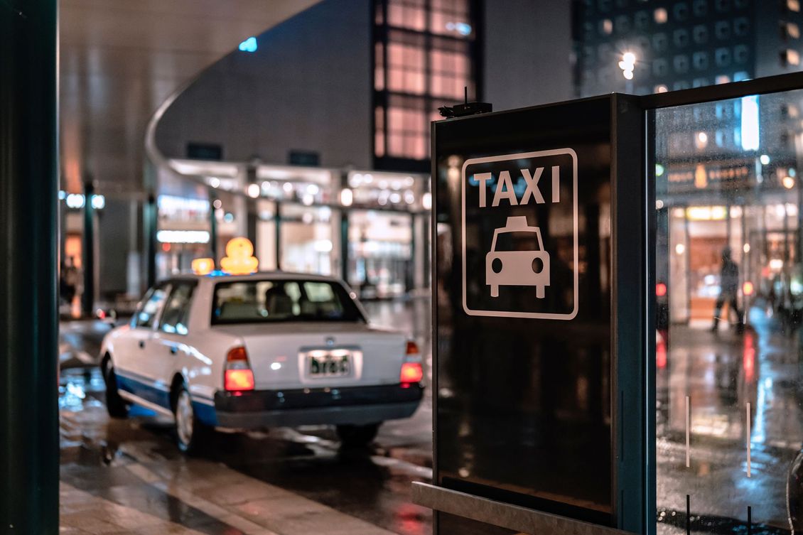 Taxi stationné dans une rue mouillée de la ville, la nuit, à côté d'un panneau noir indiquant une station de taxis.
