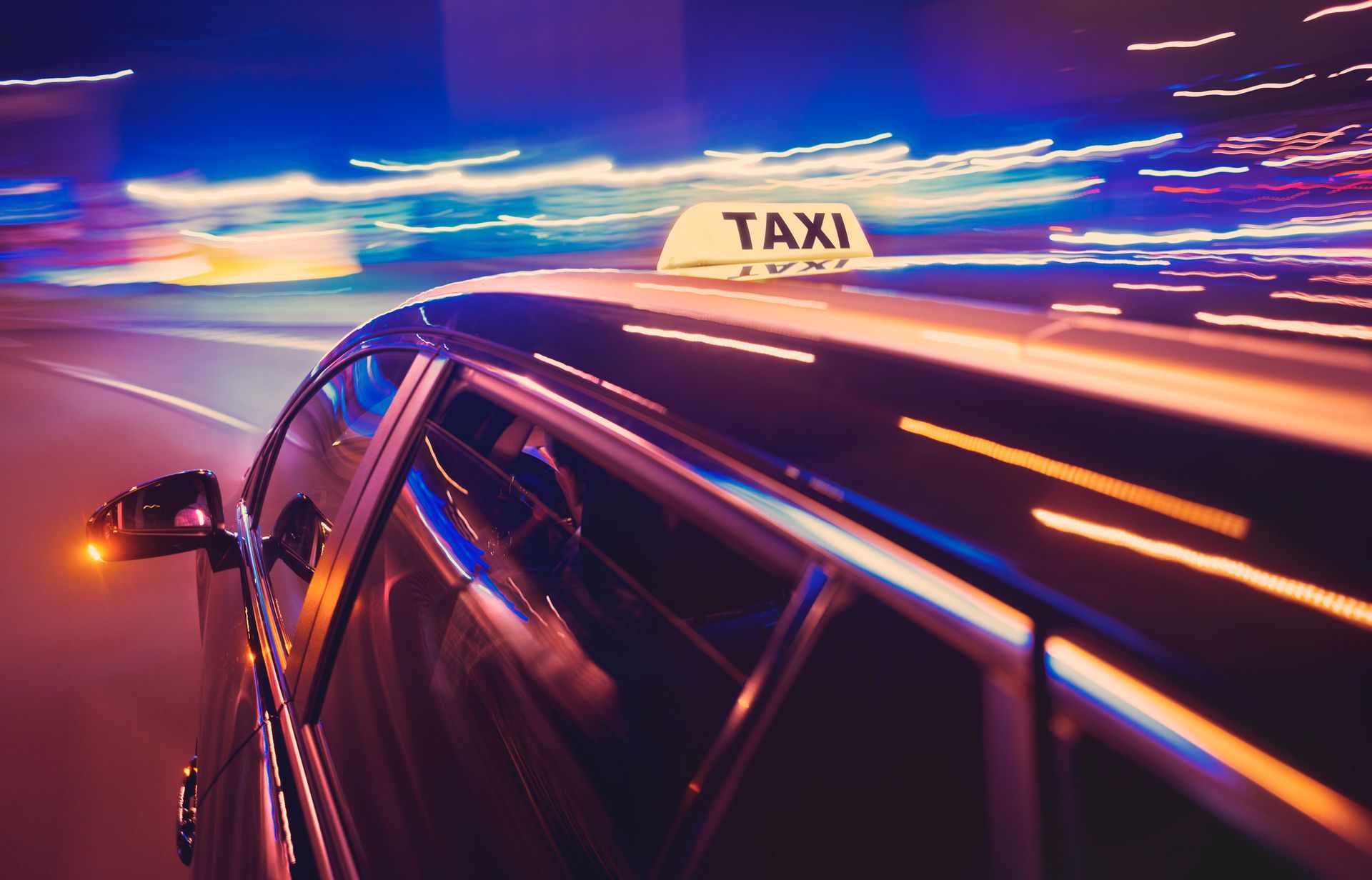 Taxi roulant de nuit avec des traînées de néon et une enseigne lumineuse sur le toit.