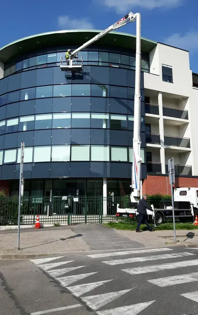 Un homme sur une nacelle nettoie les vitres d'un bâtiment