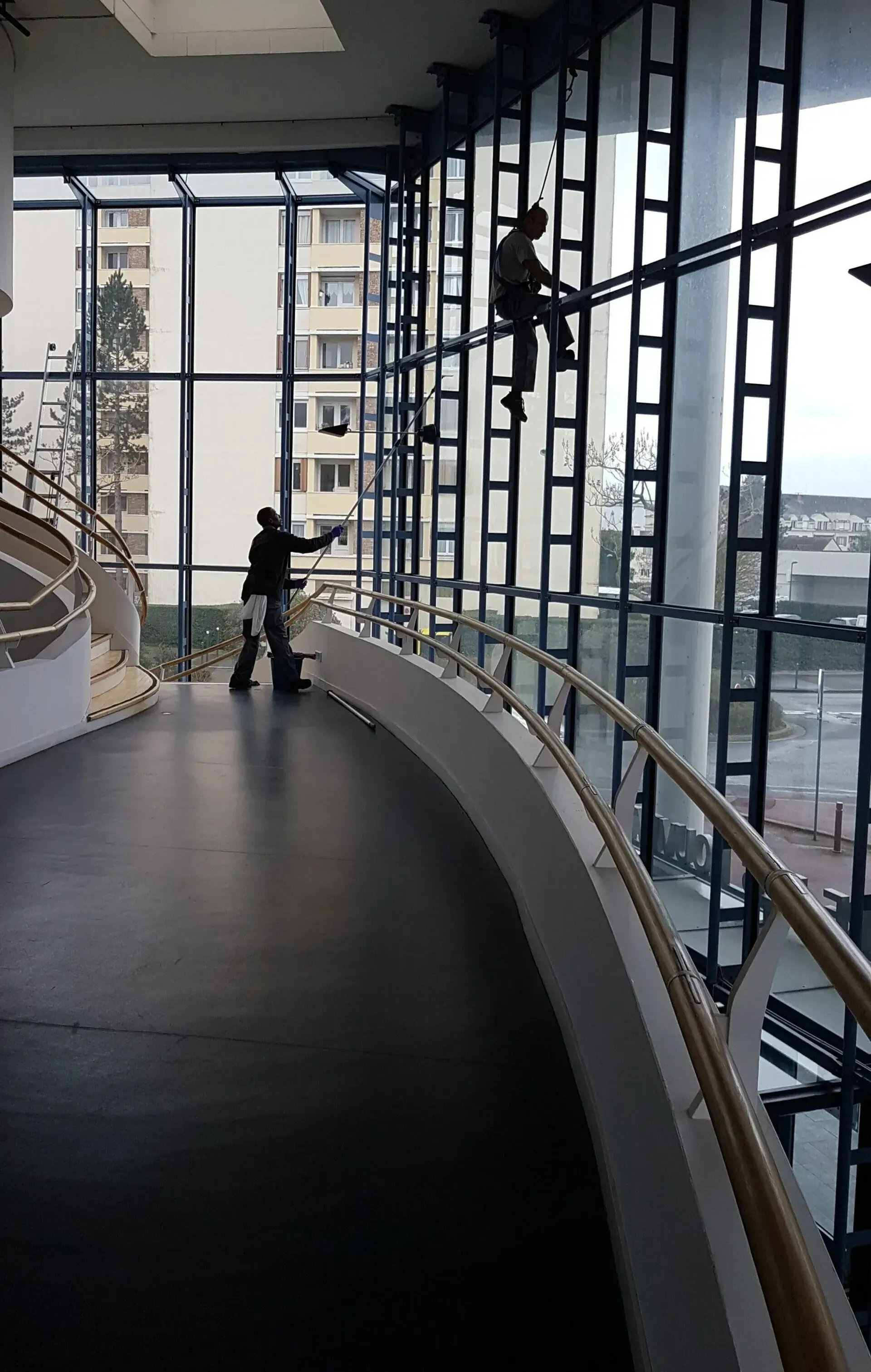 Deux hommes nettoient des vitres en hauteur