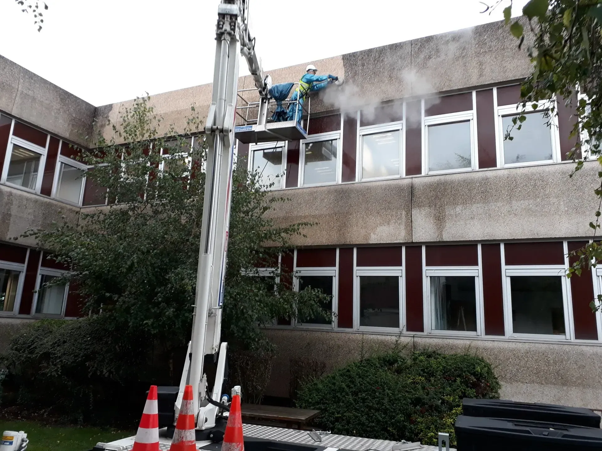 Un homme sur une nacelle nettoie la façade d'un bâtiment
