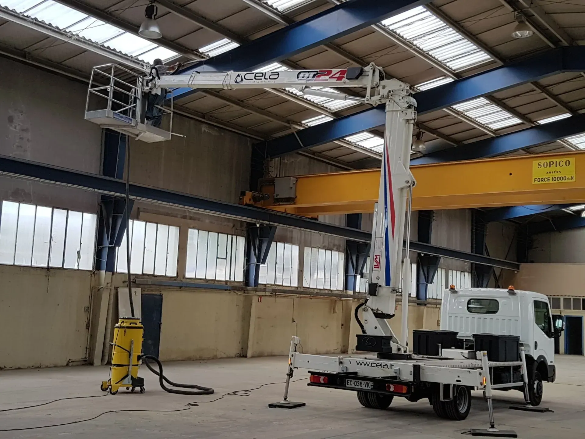 Un homme sur une nacelle nettoie un entrepôt