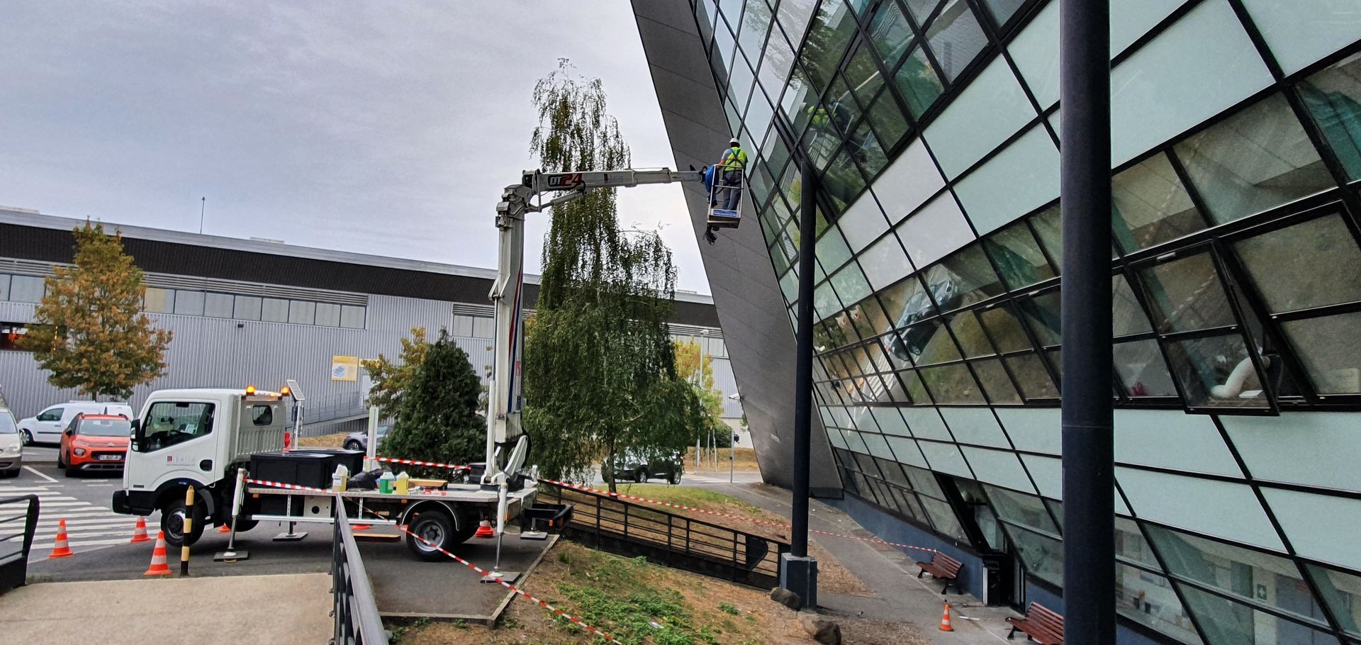 Un homme sur une nacelle devant un bâtiment vitré