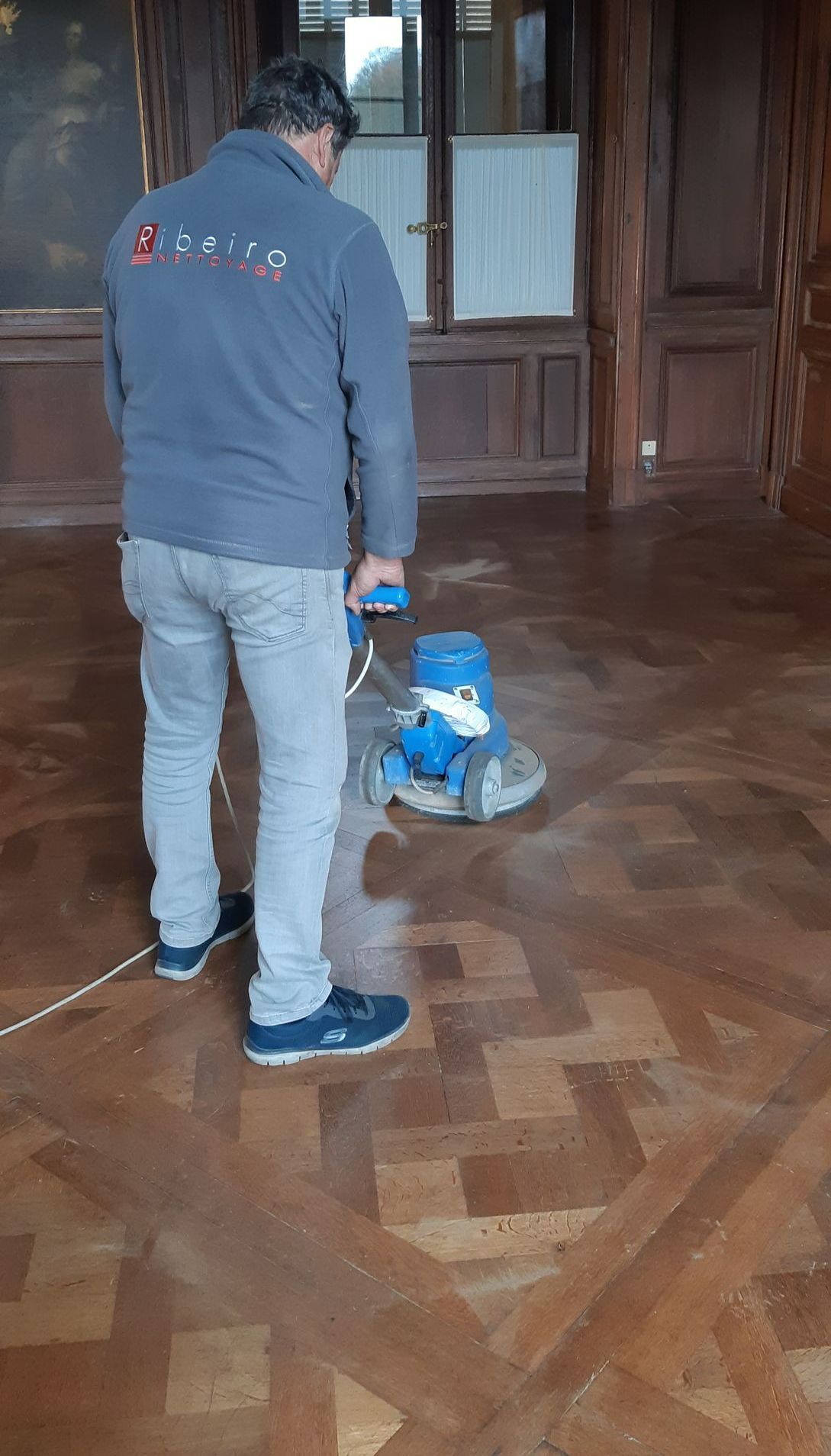 Un homme utilise une monobrosse sur un sol en bois