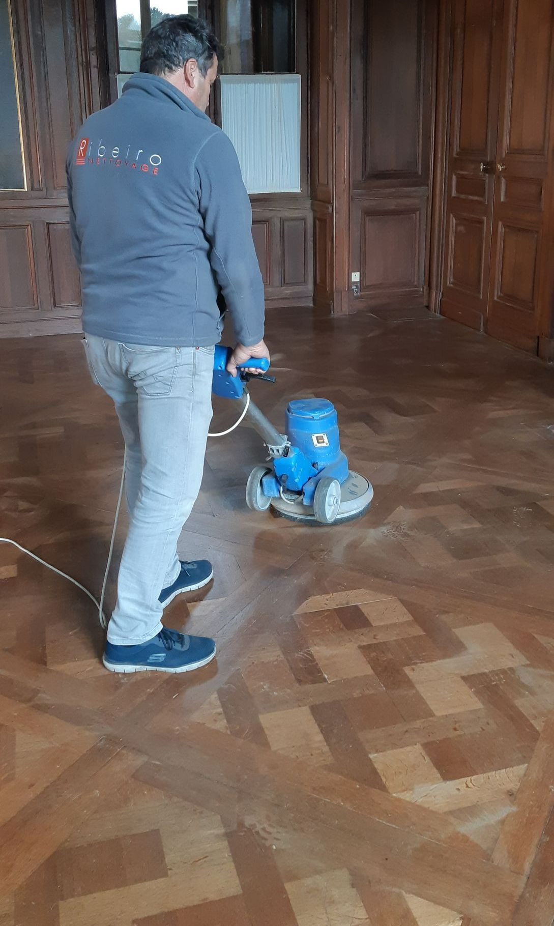 Un homme nettoie un sol en bois