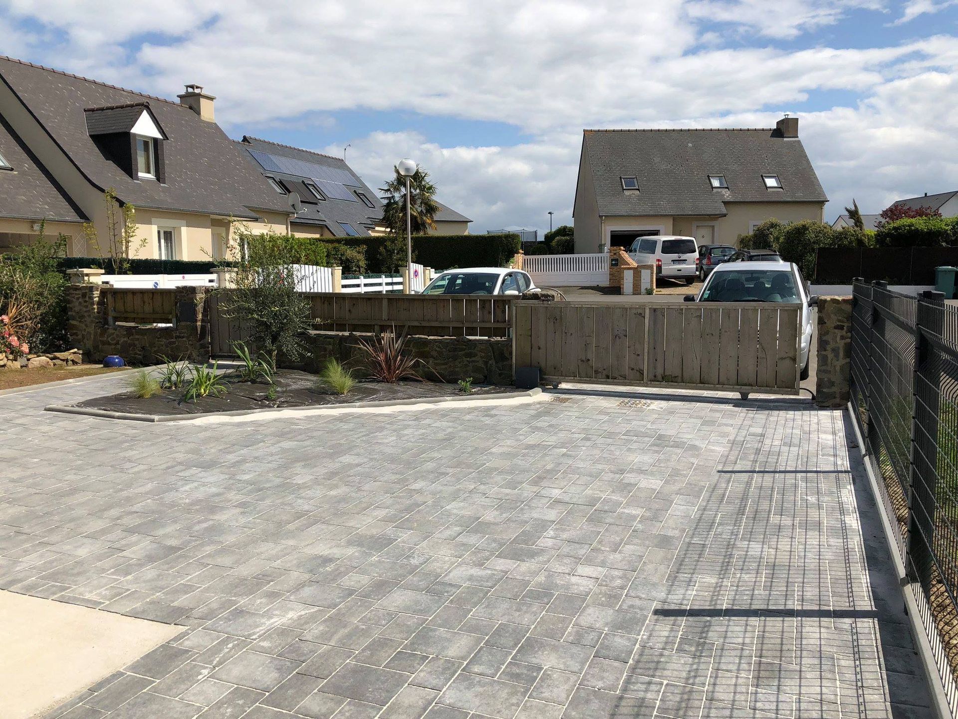 Une allée pavée menant à un portail en bois.