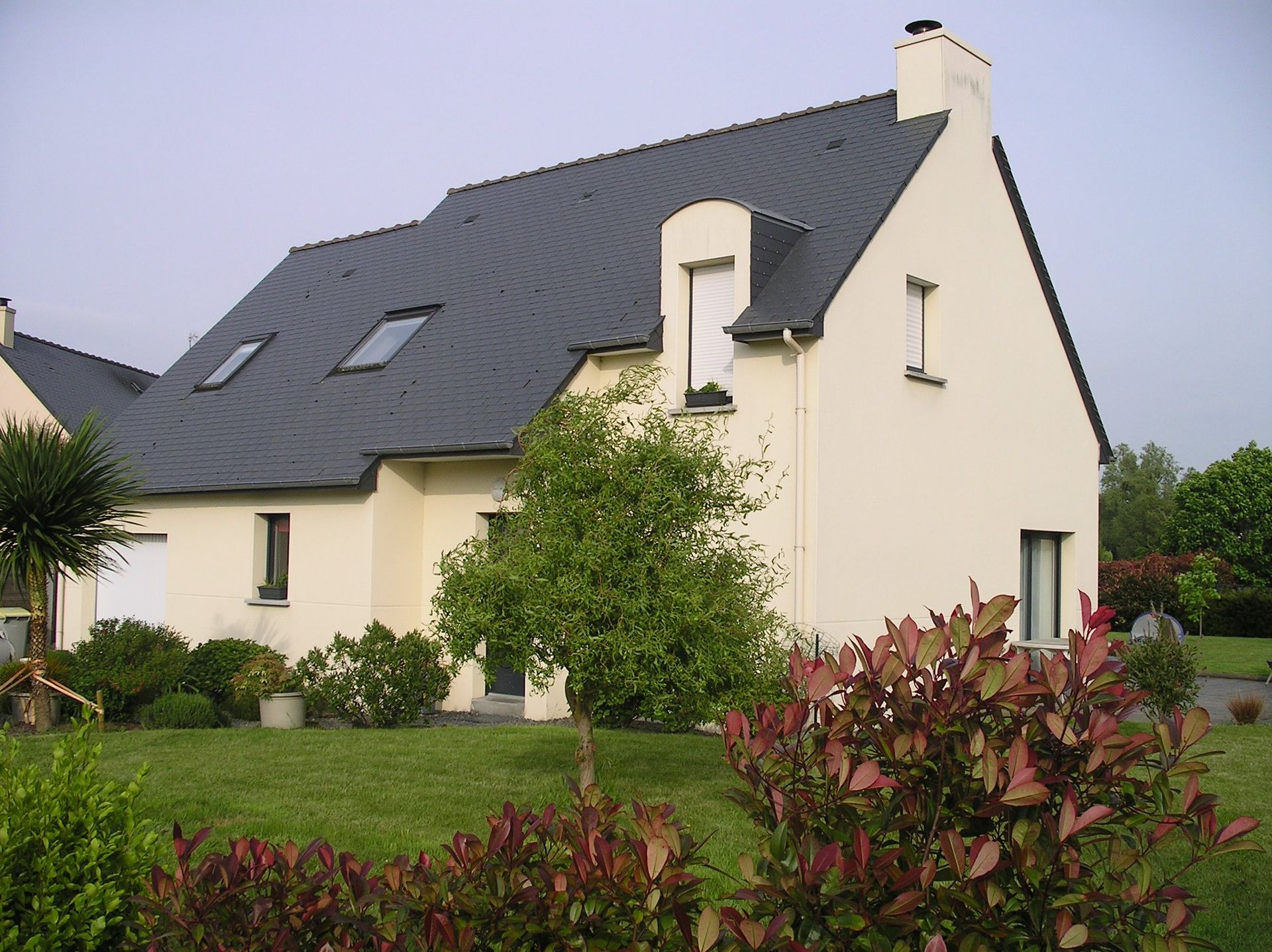 Une maison avec un toit en tuiles entourée d'une pelouse verdoyante.