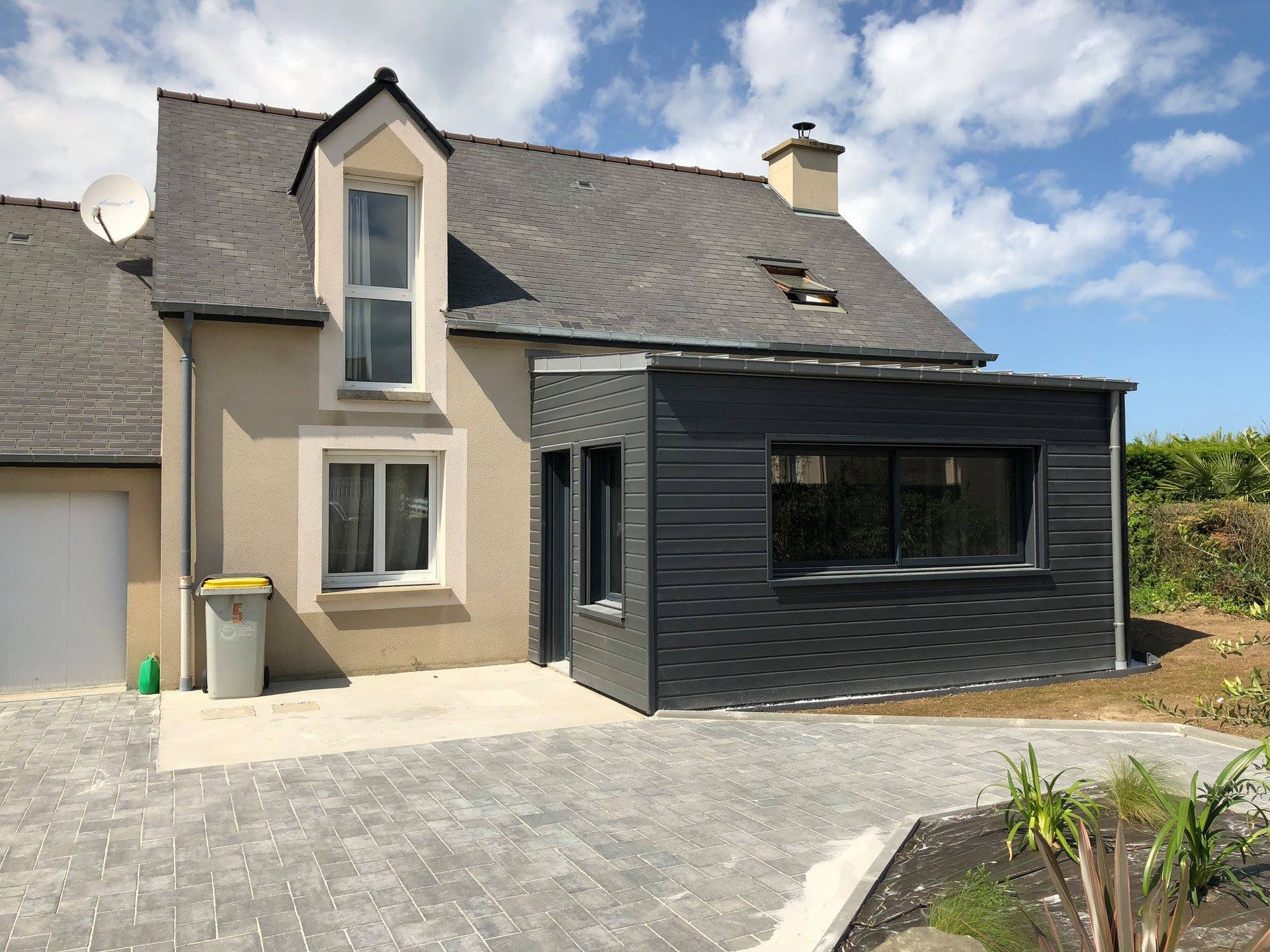 Maison avec extension et une allée en pavés.