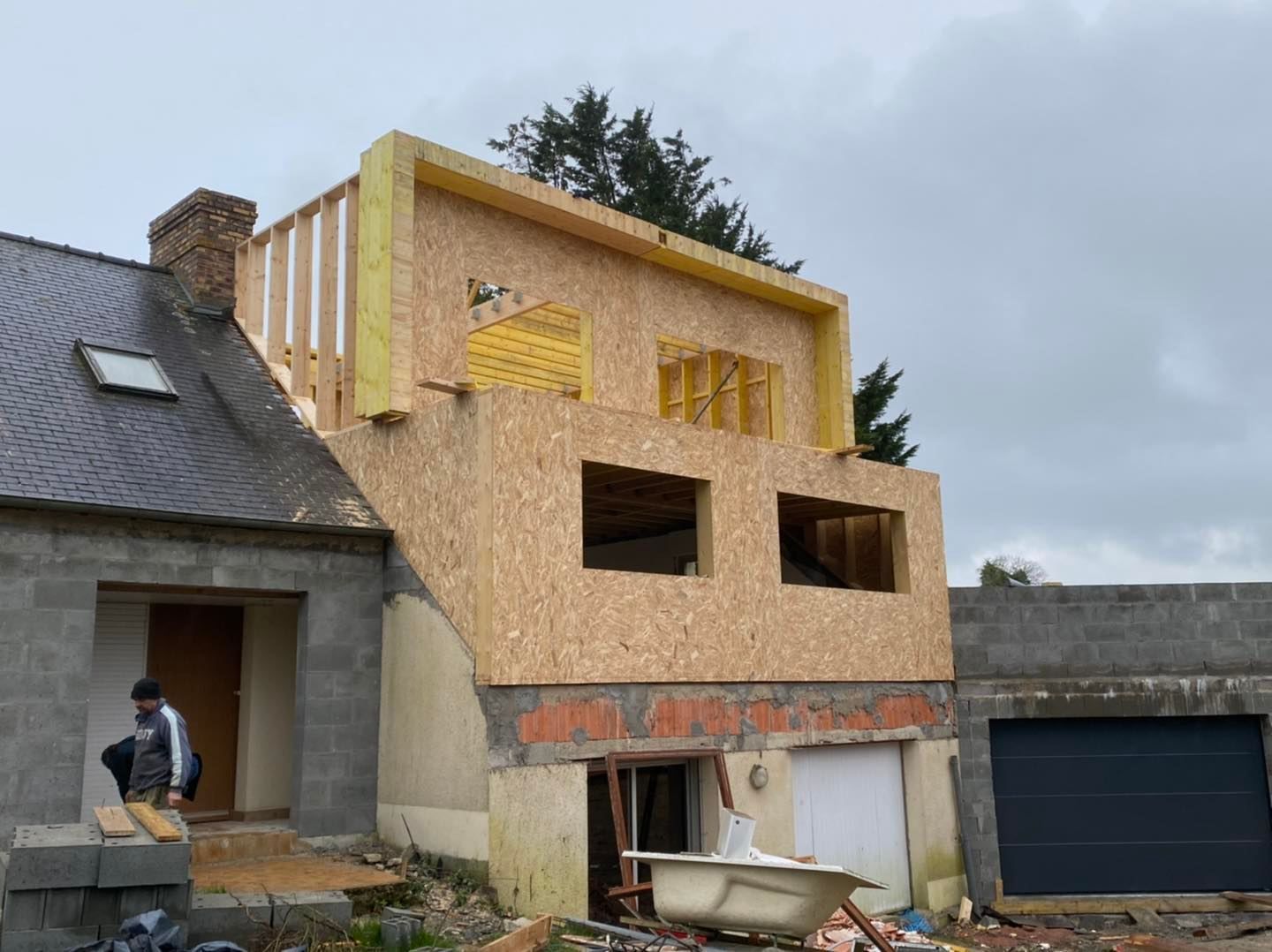 Travaux en cours sur une maison comportant une nouvelle extension en bois à l'étage.
